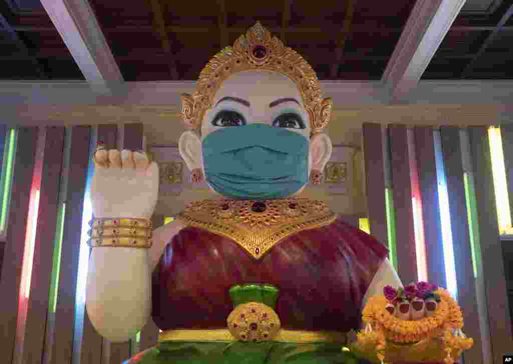 یک مجسمه بودایی در معبدی در بانکوک تایلند که ماسکی مقابل صورت آن قرار داده شده است. تایلند با سه هزار مبتلا به کرونا، تنها ۵۷ مرگ ثبت کرد.