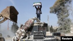 یک عضو گروه شورشیان سوری همسو با ترکیه پرچم گروهش را در عفرین بلند کرده است، یک مجسمه کردها نیز در مرکز عفرین شکسته است.