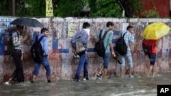 Indian boys wade through a flooded road as it rains in Jammu, India, Aug.16, 2014.
