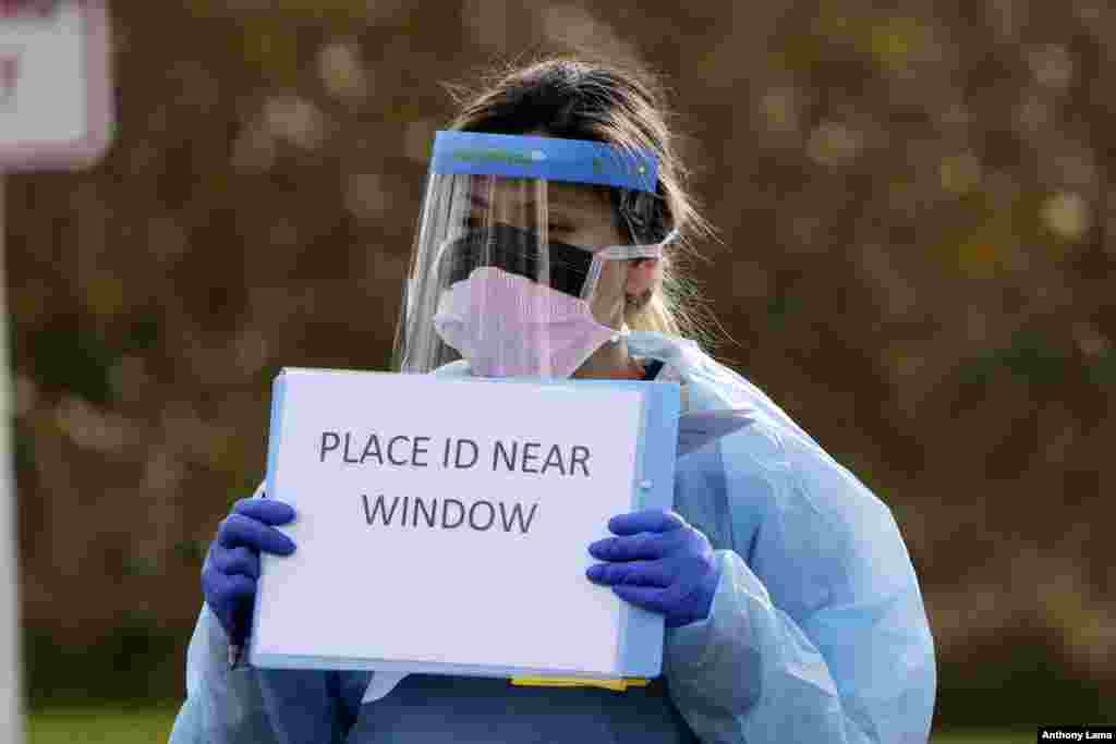 Medical assistant Miriam Fuentes gives a patient instructions via sign at a drive-through COVID-19 testing station for University of Washington Medicine patients, March 17, 2020, in Seattle, Washington.