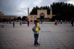 Seorang anak memegang mainan di depan Masjid Id Kah di Kashgar di Daerah Otonomi Xinjiang Uighur China, sehari sebelum liburan Idulfitri, 25 Juni 2017. (Foto: AFP)