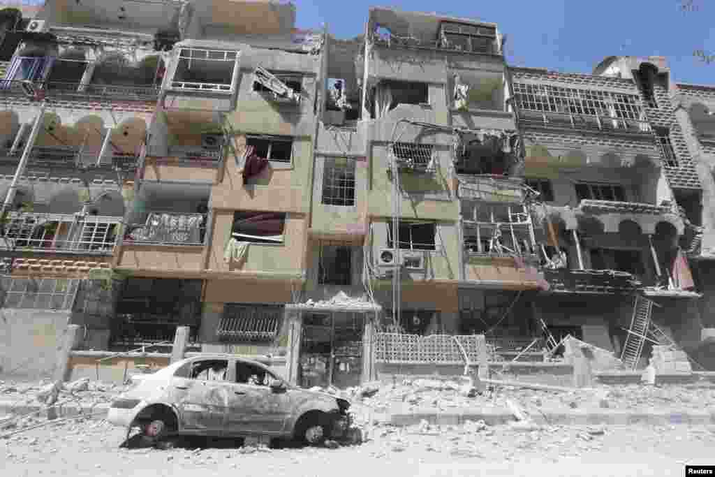 A damaged car and buildings in Al-Maliha town, in the suburbs of Damascus, April 23, 2014.