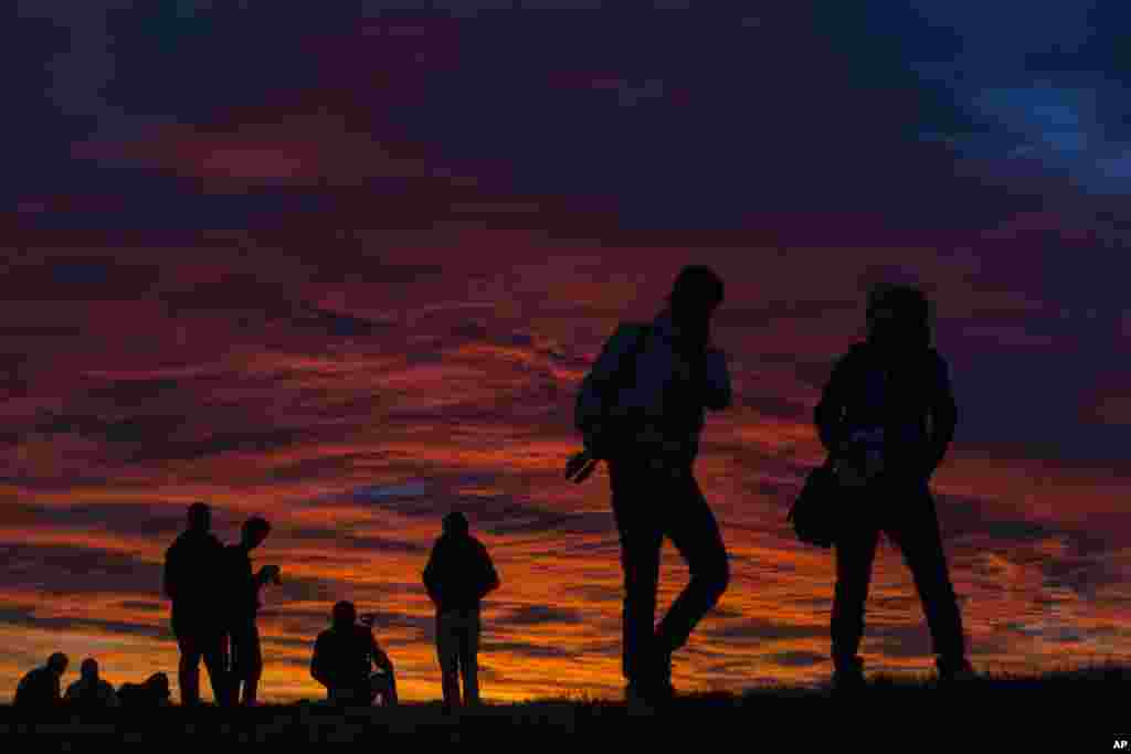 People take pictures and lay on the grass during sunset in the suburbs of Madrid, Spain.