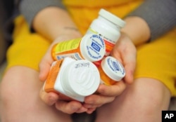 Heidi Wyandt, 27, holds a handful of her medication bottles at the Altoona Center for Clinical Research in Altoona, Pennsylvania., March 29, 2017, where she is helping test an experimental non-opioid pain medication.