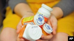 FILE - A woman holds a handful of her medication bottles at the Altoona Center for Clinical Research in Altoona, Pennsylvania, March 29, 2017, where she was helping test an experimental non-opioid pain medication.