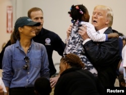 U.S. President Donald Trump lifts up a little girl as he and first lady Melania Trump visit with flood survivors of Hurricane Harvey at a relief center in Houston, Texas, Sept. 2, 2017.