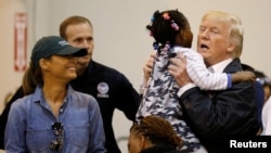 U.S. President Donald Trump lifts up a little girl as he and first lady Melania Trump visit with flood survivors of Hurricane Harvey at a relief center in Houston, Texas, Sept. 2, 2017.