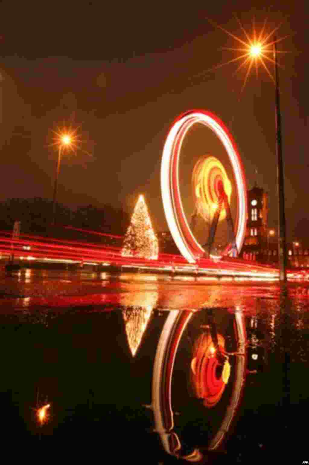 The ferris wheel at the Christmas market on the Alexanderplatz is reflected in a puddle at rainy and foggy weather in Berlin on Monday, Nov. 22, 2010. The Christmas markets in Berlin open on Monday for the Christmas season. (AP Photo/Markus Schreiber)