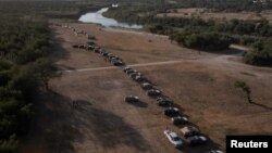 Vehículos militares y de las fuerzas del orden crean un cordón alrededor de los migrantes que se refugian en un campamento fronterizo improvisado cercano a lo largo del Puente Internacional en Del Rio, Texas, EE.UU. el 22 de septiembre de 2021. 