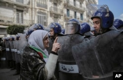 FILE - An elderly woman confronts security forces during an anti-government demonstration in Algiers, Algeria, April 10, 2019.