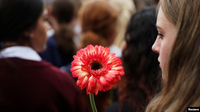 A student holds a flower during a vigil to commemorate victims of Friday's shooting, outside Masjid Al Noor mosque in Christchurch, New Zealand March 18, 2019.