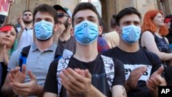 Young opposition demonstrators wearing masks reading "Russia Occupant " gather in front of the Georgian Parliament building in Tbilisi, Georgia, June 21, 2019.