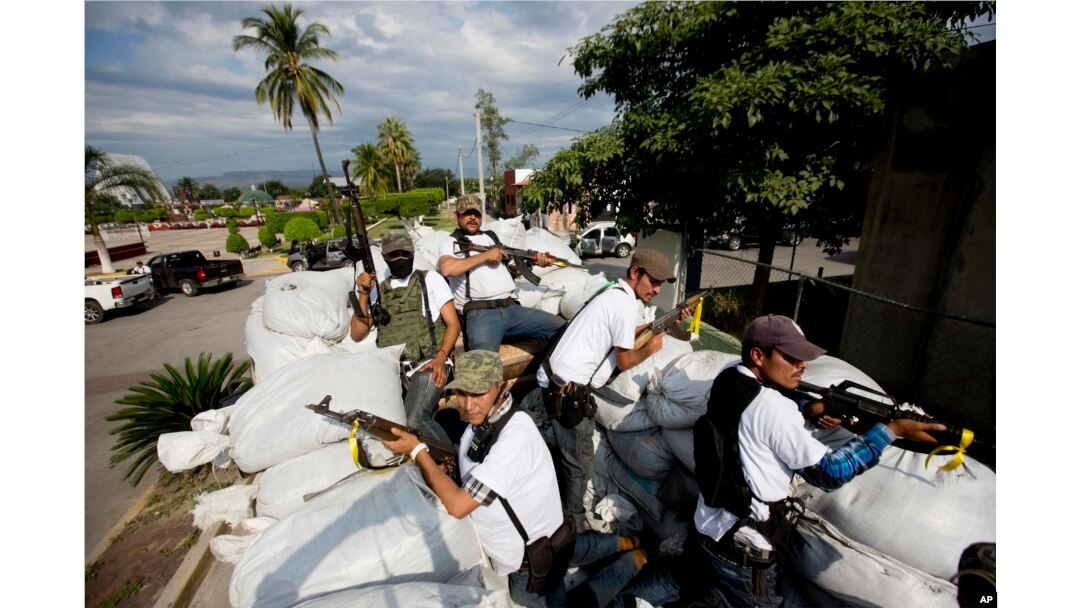 FILE - Men belonging to the Self-Defense Council of Michoacan ride on a sandbag-filled truck while trying to flush out alleged members of The Caballeros Templarios drug cartel from the town of Nueva Italia, Mexico, Jan. 12, 2014.