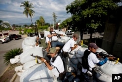 FILE - Men belonging to the Self-Defense Council of Michoacan ride on a sandbag-filled truck while trying to flush out alleged members of The Caballeros Templarios drug cartel from the town of Nueva Italia, Mexico, Jan. 12, 2014.