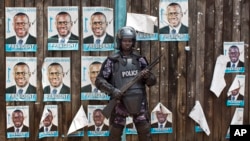 A Ugandan riot policeman blocks the gate of the party headquarters of opposition leader Kizza Besigye, shortly after raiding the premises for the second time in a week, in the capital Kampala, Feb. 22, 2016. 