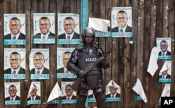A Ugandan riot policeman blocks the gate of the party headquarters of opposition leader Kizza Besigye, shortly after raiding the premises for the second time in a week, in the capital Kampala, Uganda, Feb. 22, 2016.