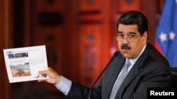 El presidente de Venezuela, Nicolás Maduro, sostiene una pancarta que dice "Imágenes falsas presentadas por Ivan Duque en la ONU" e "Imágenes incorrectas crean dudas en el informe entregado a la ONU" durante una conferencia de prensa en Caracas, Venezuela, el lunes.