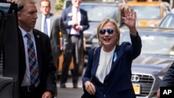 Democratic presidential candidate Hillary Clinton waves as she walks from an apartment building, Sept. 11, 2016, in New York. 