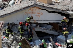 Rescuers mark a building with paint signaling the date and time of start and end of the search operation on that building, following Wednesday's earthquake in Pescara Del Tronto, Italy, Aug. 25, 2016.