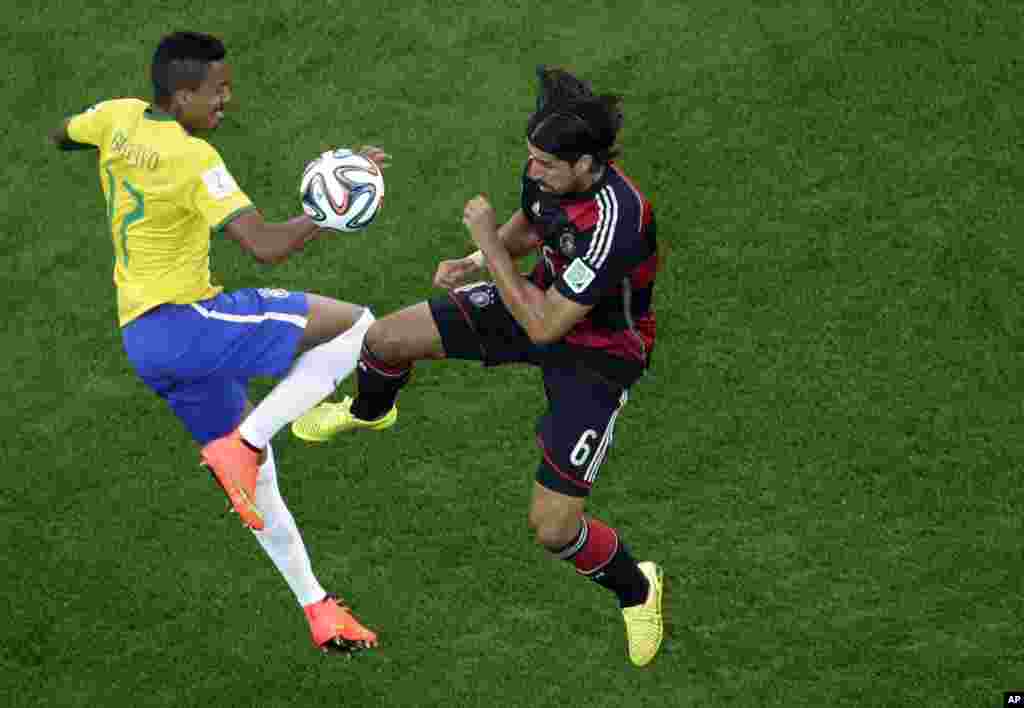 Brazil's Luiz Gustavo and Germany's Sami Khedira go for the ball during the World Cup semifinal soccer match between Brazil and Germany at the Mineirao Stadium in Belo Horizonte, Brazil, July 8, 2014. 