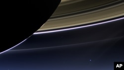 This July 19, 2013 image made available by NASA shows Saturn's rings and planet Earth, center right, as seen from the Cassini spacecraft. 