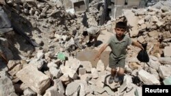 A boy walks on the rubble of buildings damaged by what activists said were missiles fired by Syrian Air Force fighter jets loyal to President Bashar al-Assad in Salqin city, Idlib governate, May 28, 2013.