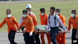 Personel Basarnas menggotong jasad korban pesawat AirAsia penerbangan 8501, yang baru tiba dari helikopter di bandara Pangkalan Bun, Kamis (1/1).