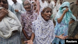 Women grieve and wait outside a building for their relatives after a fire at a garment factory in Karachi September 12, 2012. 