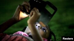 FILE - A girl uses a mobile phone in Khartoum, Sudan. In neighboring South Sudan, the government cut the signal on the Vivacell telecom firm this week, alleging it had not paid licensing fees.
