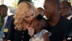 US musician Madonna, kisses one of her adopted daughters Stella, as son David Banda, right, looks on at the opening of The Mercy James Institute for Pediatric Surgery and Intensive Care, located at the Queen Elizabeth Central Hospital in the city of Blant