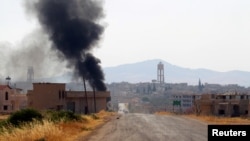 FILE - Smoke rises from Taybat al Imam town after rebel fighters from the hardline jihadist Jund al-Aqsa advanced in the town in Hama province, Syria, August 31, 2016. 