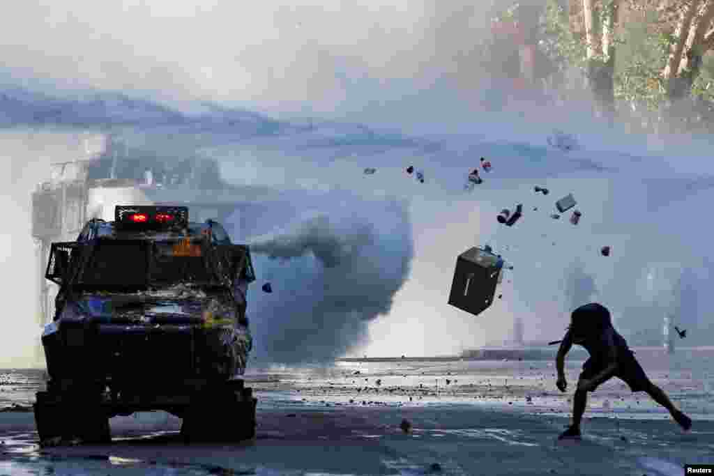 A demonstrator throws items at an armored vehicle during a protest against Chile&#39;s government in Santiago, Dec. 30, 2019.