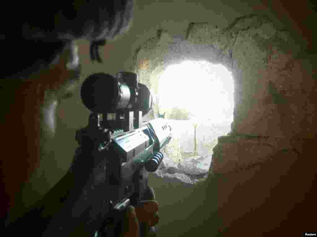 A member of the Free Syrian Army points his weapon through a hole in a wall as he takes up a defense position in a house in Qusseer neighborhood in Homs, Syria, July 16, 2012.