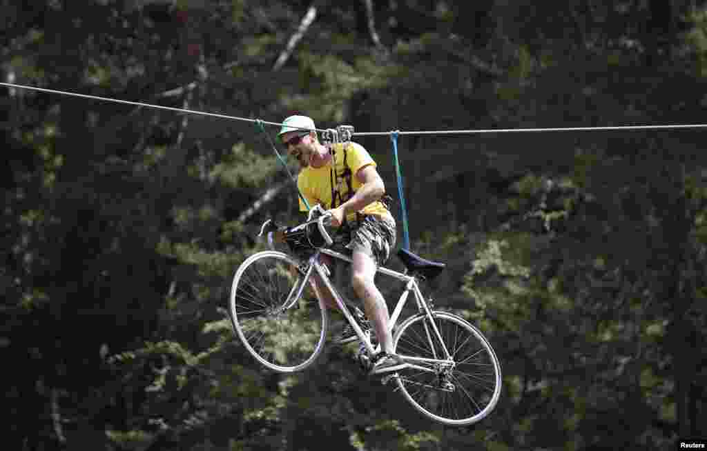 Seorang pesepeda mengendarai sepedanya yang tergantung di sebuah kabel pada putaran ke-17 Tour de France ke-102 dari Digne-les-Bains ke Pra Loup di pegunungan Alpen Perancis.