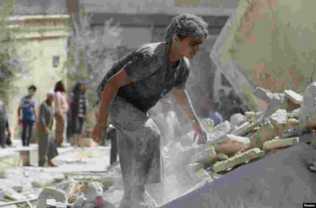 A man looks for survivors under the rubble of collapsed buildings after what activists said was a vacuum bomb dropped by forces of Syria's President Bashar al-Assad on Maarat Al-Nouman, south of Idlib.