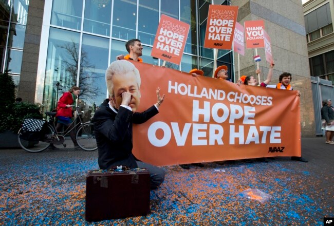 A man poses as crying firebrand anti-Islam lawmaker Geert Wilders during a small demonstration outside parliament, rear, in The Hague, Netherlands, March 16, 2017.