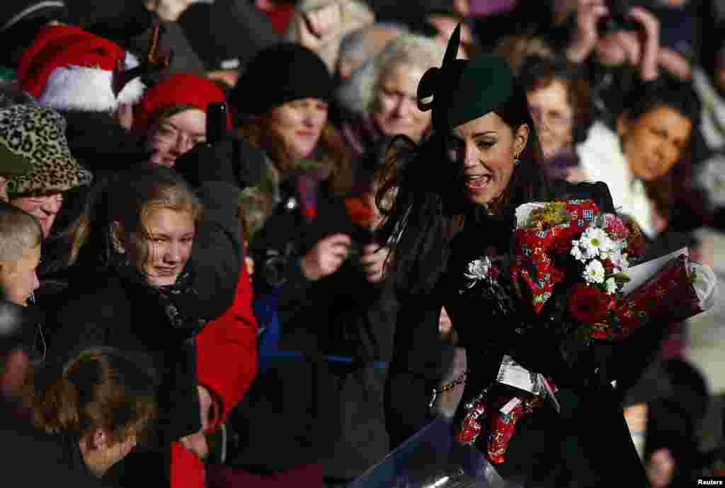 A Princesa Kate do Reino Unido corre para receber as flores do povo que espera por ela à saída da missa de Natal na Igreja de Sandringham em Norfolk, Inglaterra.