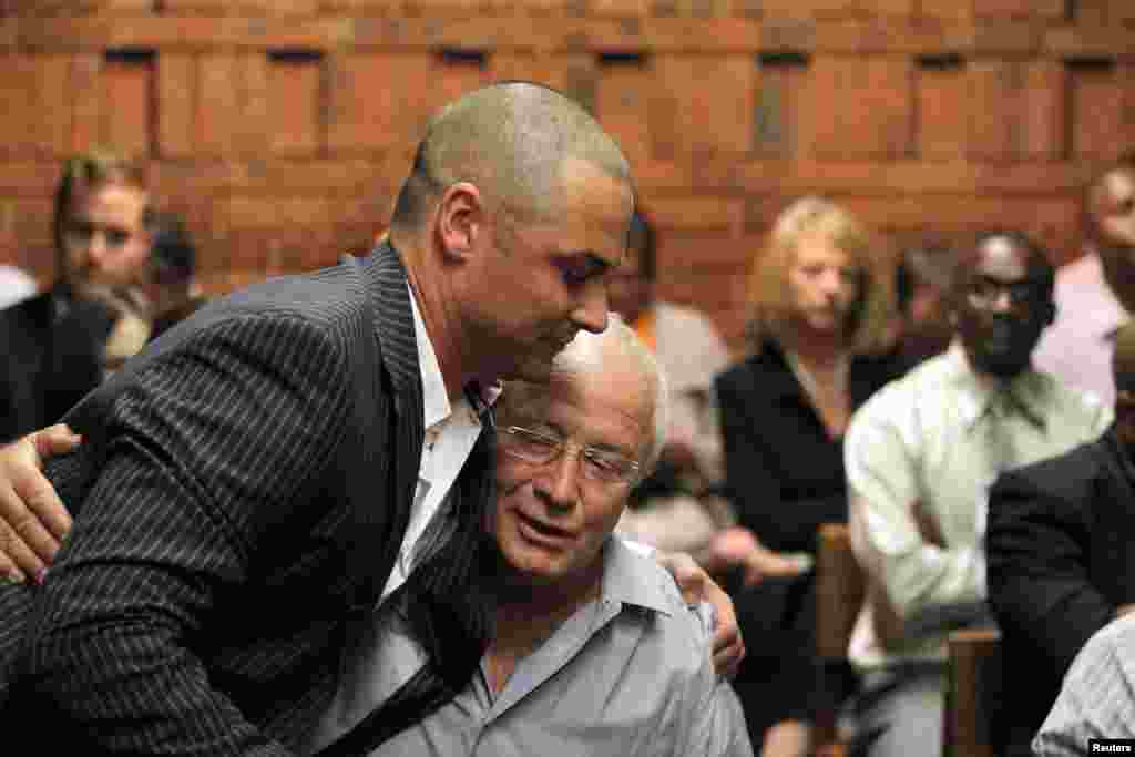 Oscar Pistorius' brother Carl hugs his father Henke at the Pretoria Magistrates court, February 21, 2013.