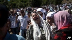 A woman cries as the remains of her son are buried at the Potocari memorial complex near Srebrenica.
