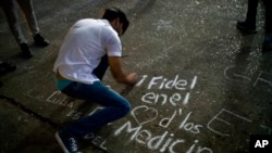 A student writes on a sidewalk with chalk "Fidel in the hearts of the med students" during a vigil for the late Cuban leader Fidel Castro at the university where Castro studied law as a young man in Havana, Cuba, Nov. 26, 2016. 