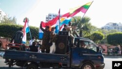 Supporters onboard a car wave national and military flags Tuesday, Feb. 2, 2021, in Yangon, Myanmar. Hundreds of members of Myanmar's Parliament remained confined inside their government housing in the country's capital on Tuesday, a day after the militar