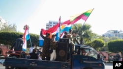 Supporters onboard a car wave national and military flags Tuesday, Feb. 2, 2021, in Yangon, Myanmar. Hundreds of members of Myanmar's Parliament remained confined inside their government housing in the country's capital on Tuesday, a day after the militar