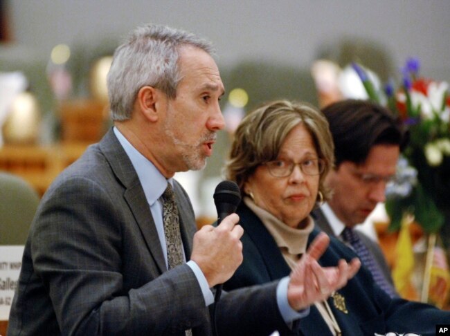 FILE - Democratic state Rep. Daymon Ely of Corrales, N.M., left, explains provisions of a bill he sponsored with Rep. Joy Garratt of Albuquerque, center, that would allow police or family members to seek court orders requiring people who are deemed threatening to surrender their guns, in Santa Fe, N.M., Feb. 4, 2019.