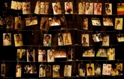 FILE - Family photographs of some of those who died hang on display in an exhibition at the Kigali Genocide Memorial in the capital Kigali, Rwanda, April 5, 2019.