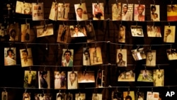 FILE - Family photographs of some of those who died hang on display in an exhibition at the Kigali Genocide Memorial centre in the capital Kigali, Rwanda, April 5, 2019. 