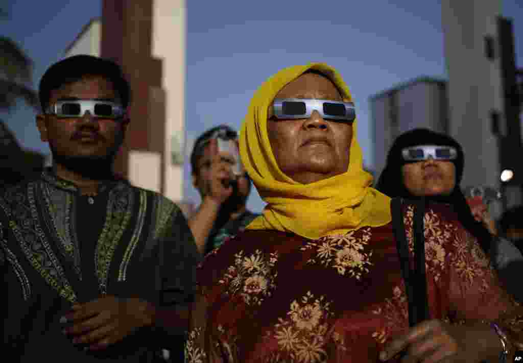 Warga menyaksikan gerhana matahari total menggunakan kacamata pelindung di Jakarta (9/3). (AP/Dita Alangkara)