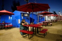 A person living in the village eats at a community table, February 25, 2021, in the North Hollywood section of Los Angeles. (AP Photo/Marcio Jose Sanchez)