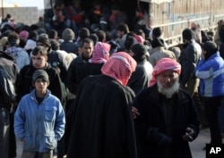 In this photo provided by Turkey's Islamic aid group of IHH, Syrians fleeing the conflicts in Azaz region, arrive in a truck at the Bab al-Salam border gate, Syria, Feb. 5, 2016.