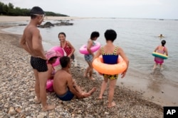 In this Aug. 20, 2018, photo, North Koreans enjoy the day on a seashore near Mount Chilbo, North Korea.