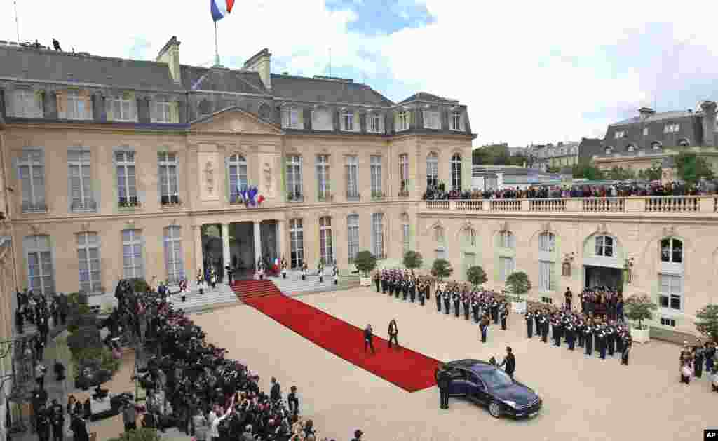 Nicolas Sarkozy and his wife Carla Bruni-Sarkozy, center, leave the Elysee Palace after the handover ceremony.